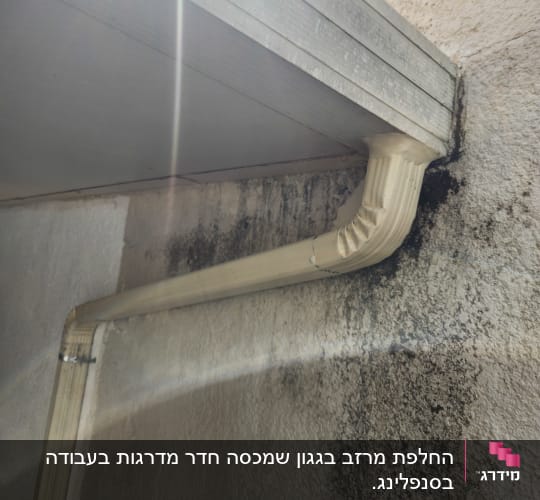 צינור ניקוז מותקן על קיר חיצוני עם סימני רטיבות